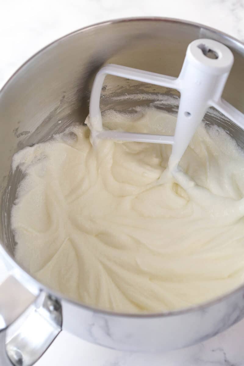 Adding vanilla extract and sour cream to creamed butter, oil, and sugar for cake batter.