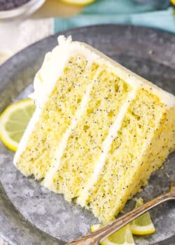 A slice of Lemon Poppyseed Cake next to a fork on a gray plate