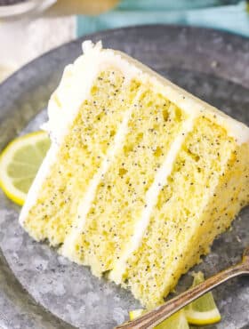 A slice of Lemon Poppyseed Cake next to a fork on a gray plate