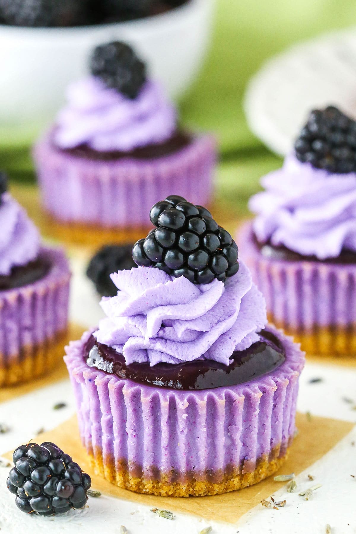 Side view of Mini Blackberry Lavender Cheesecakes on a white table top
