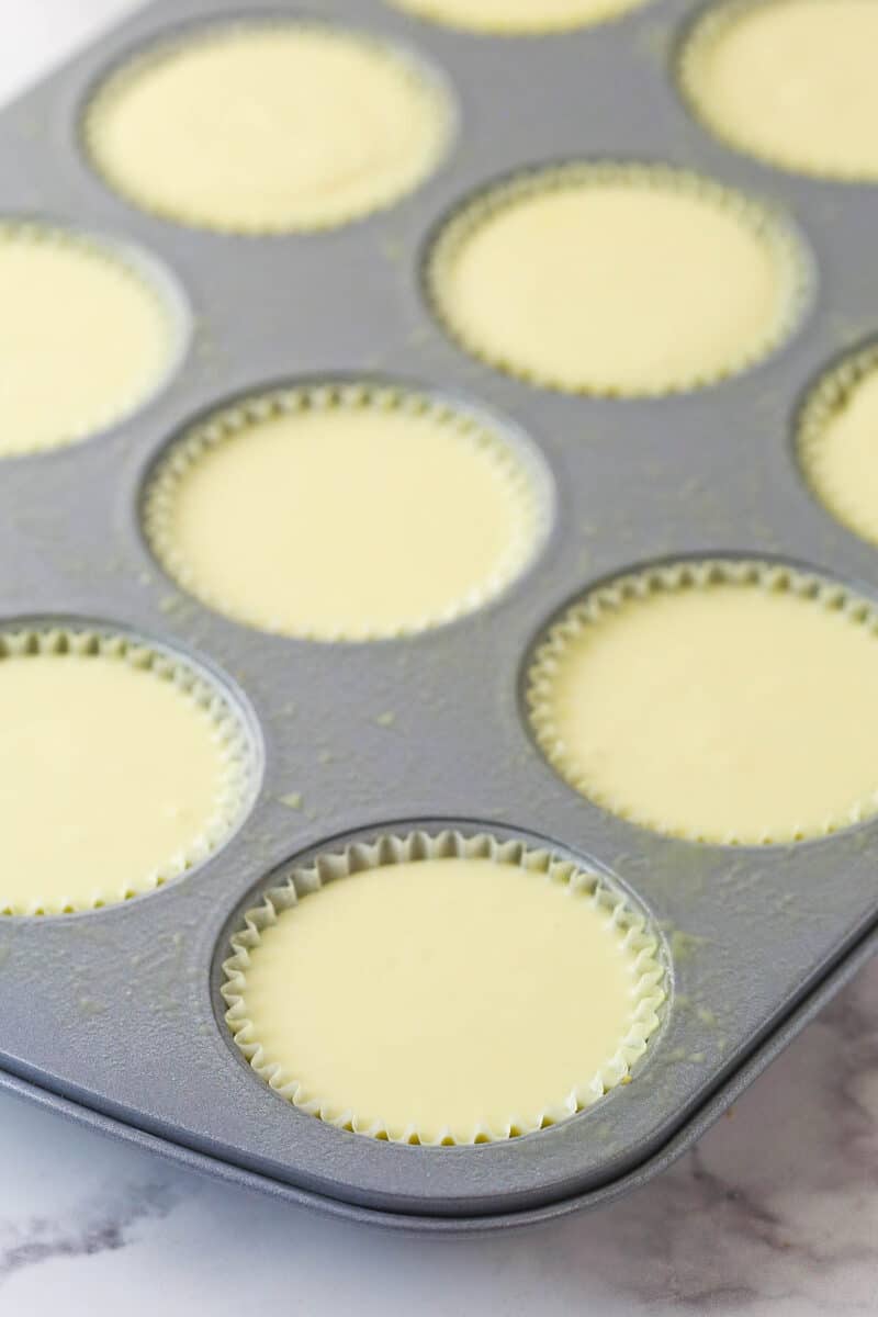 Mini cheesecakes in a muffin pan ready to be baked.