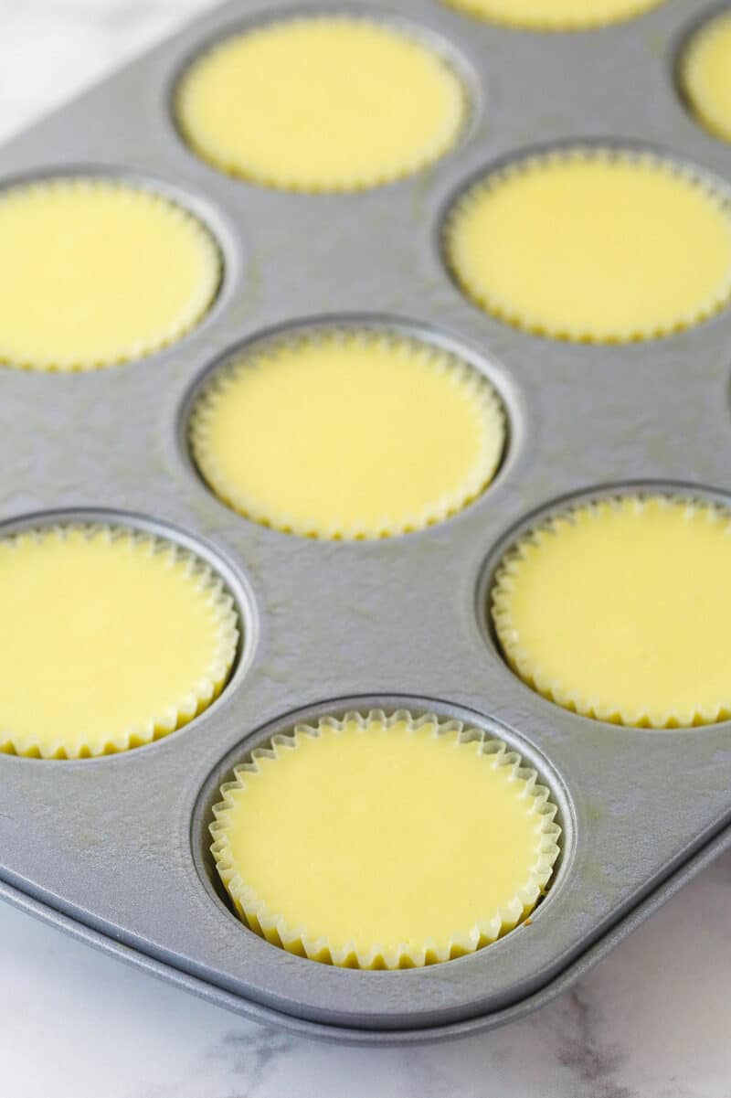 Mini cheesecakes cooling in a muffin pan.