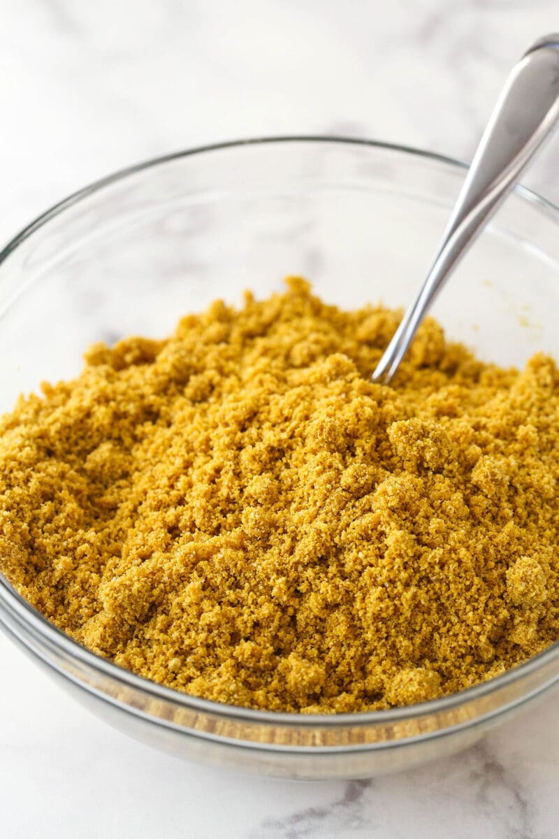 Butter, sugar, and graham cracker crumbs mixed together in a bowl.