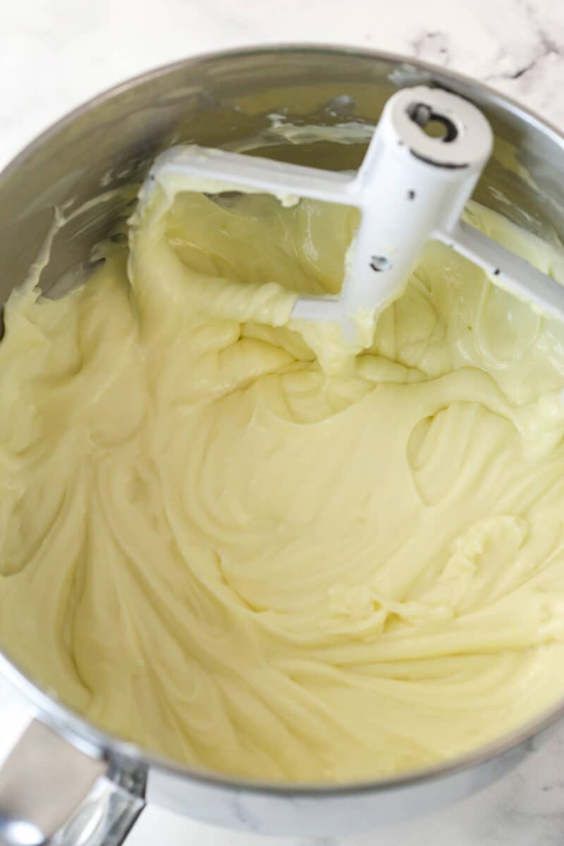 Mixing lemon zest and heavy cream into cheesecake filling.