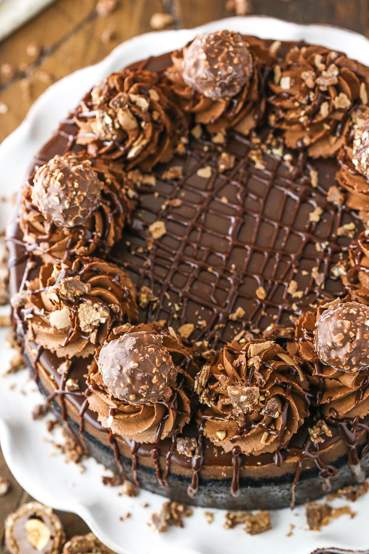 This Nutella Cheesecake is thick, creamy, rich and flat out amazing! It's baked in an Oreo crust and topped with Nutella ganache and I'm totally obsessed with it! Overhead view of Nutella Cheesecake on a white cake stand