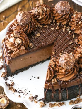 Nutella Cheesecake with a slice removed on a white cake stand