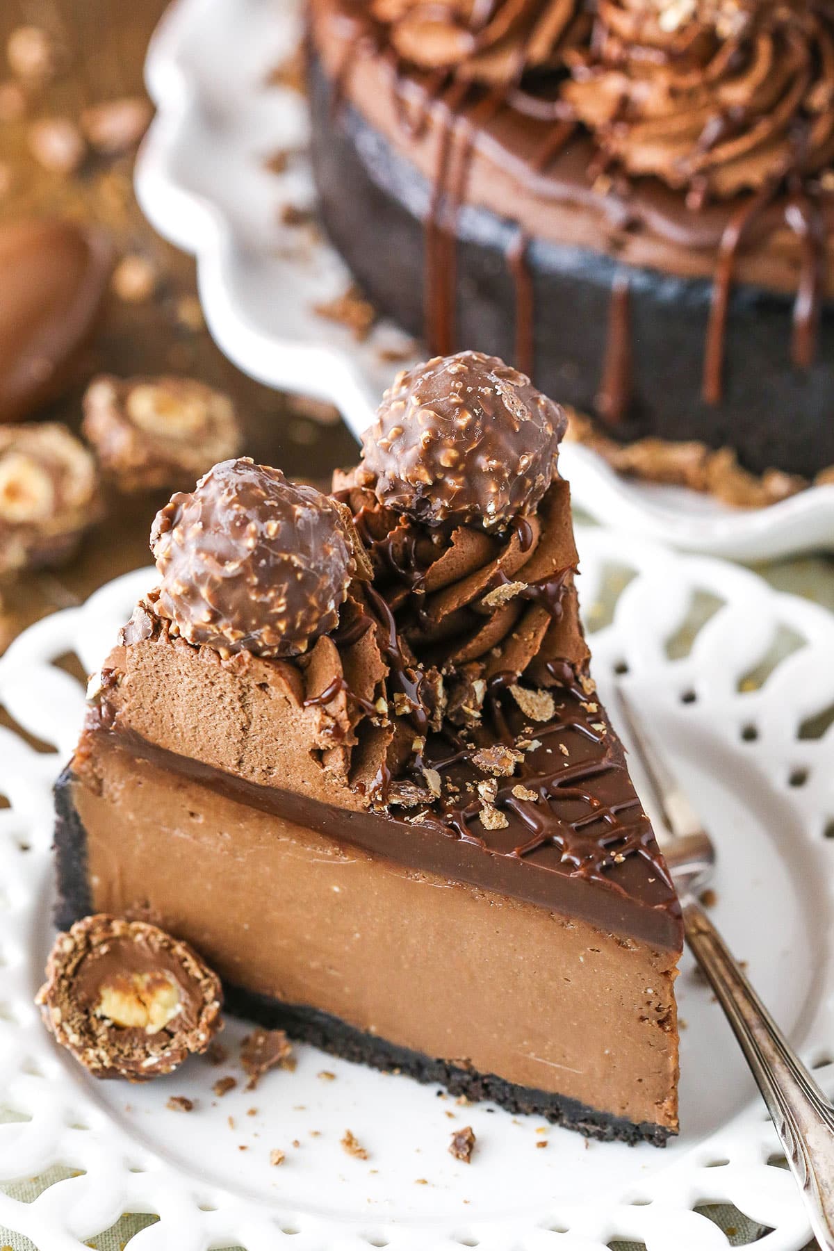 A slice of Nutella Cheesecake next to a fork on a white plate