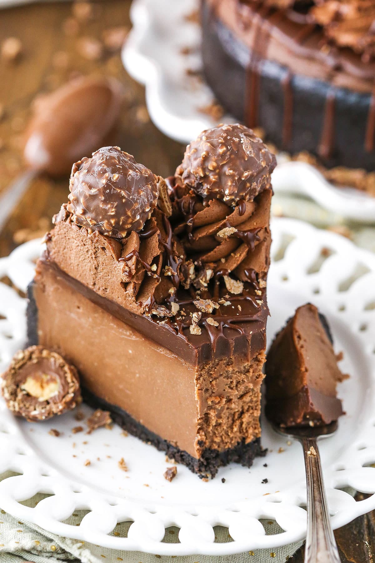 A slice of Nutella Cheesecake with a bite removed next to a fork on a white plate