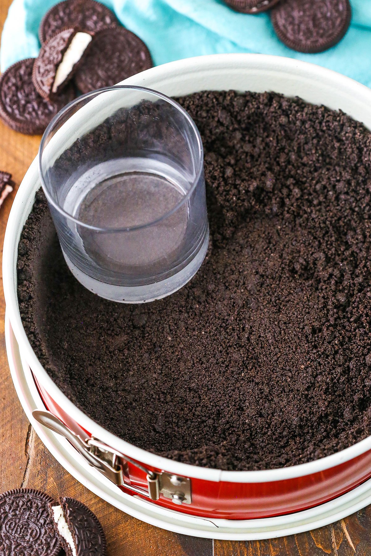 A step in making Oreo Cookie Crust showing the crust mixture pressed into the bottom and up the sides of a springform pan