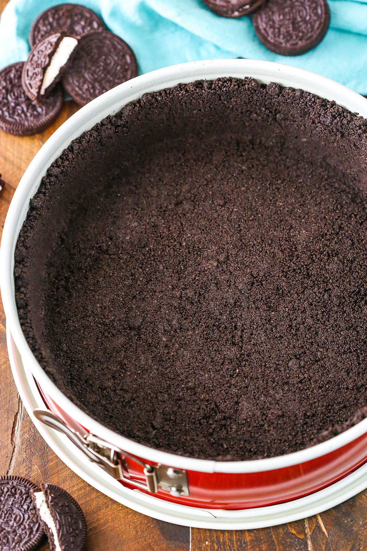 Oreo Cookie Crust in a red springform pan on a wooden table