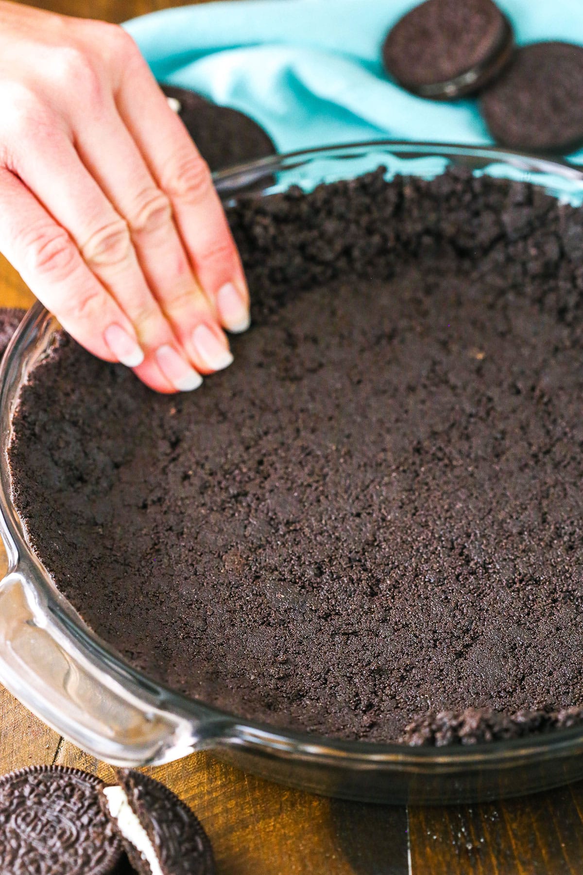 Oreo Cookie Crust being pressed into a clear glass pan