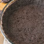 Oreo Cookie Crust in a clear glass pan on a wooden table