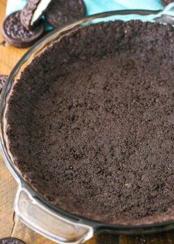 Oreo Cookie Crust in a clear glass pan on a wooden table