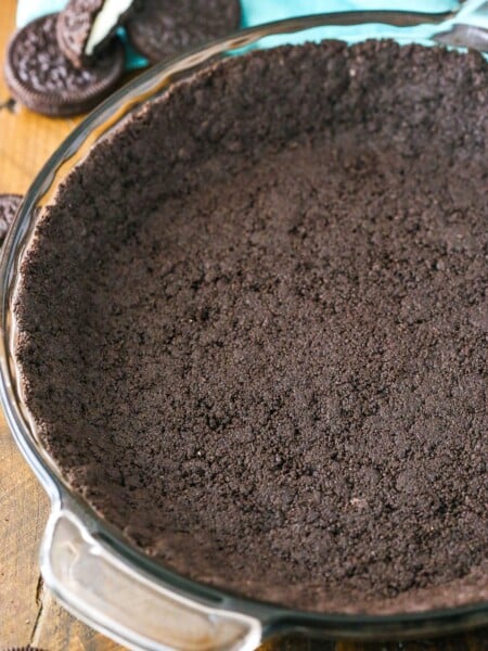 Oreo Cookie Crust in a clear glass pan on a wooden table