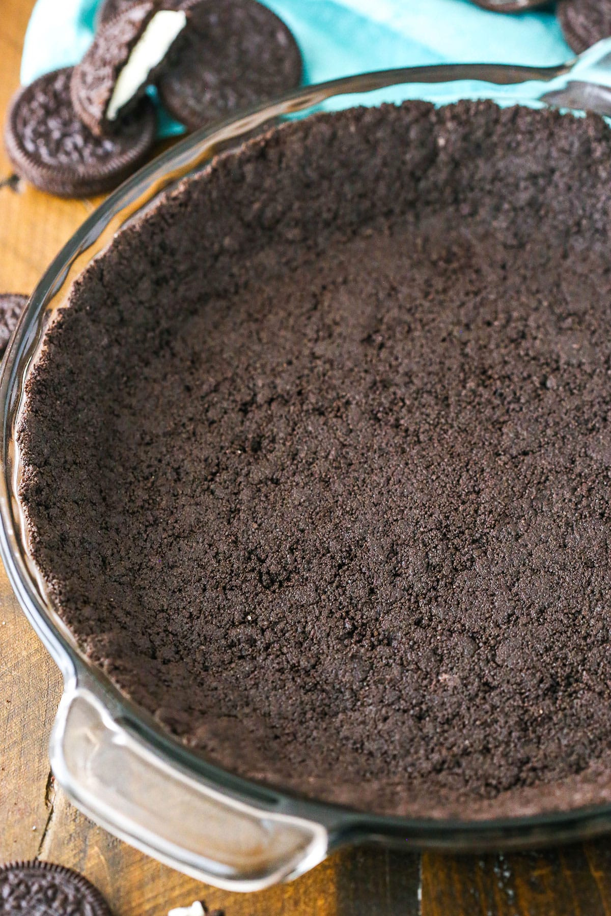 Oreo Cookie Crust in a clear glass pan on a wooden table