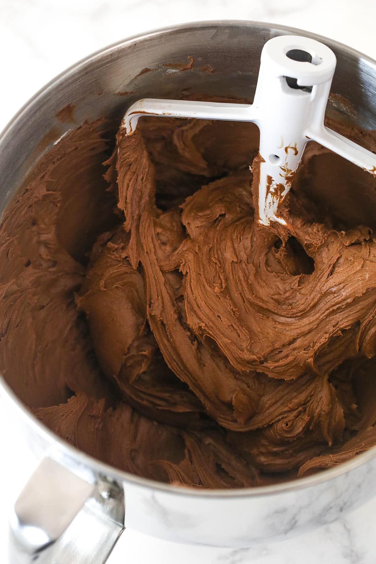 This chocolate raspberry cake is made of moist chocolate cake, smooth raspberry filling, dark chocolate frosting, and rich chocolate ganache. Chocolate frosting in a mixing bowl.