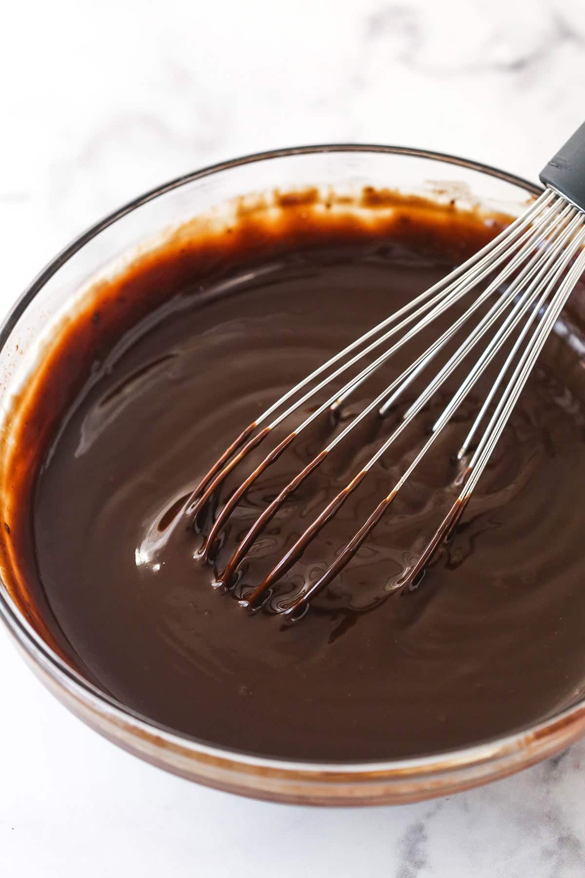 whisking together melted chocolate chips and heavy cream to make chocolate ganache.