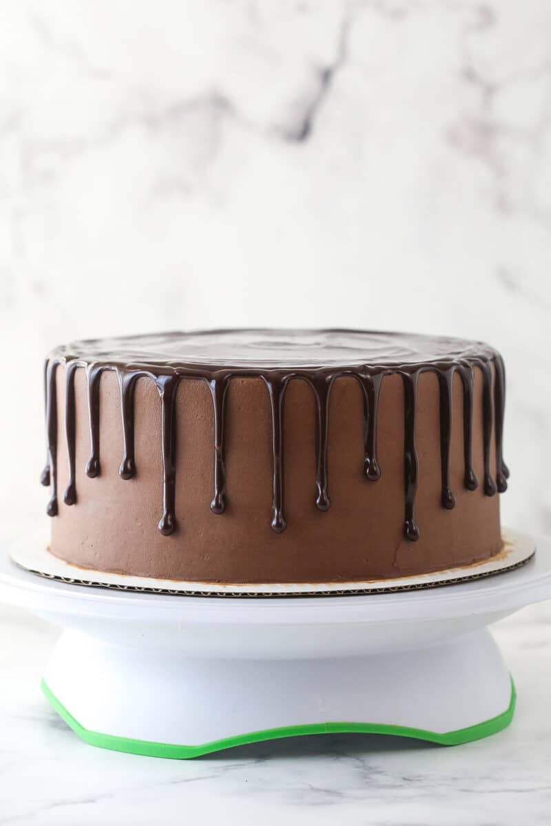 This chocolate raspberry cake is made of moist chocolate cake, smooth raspberry filling, dark chocolate frosting, and rich chocolate ganache. Drizzling chocolate raspberry cake with chocolate ganache.