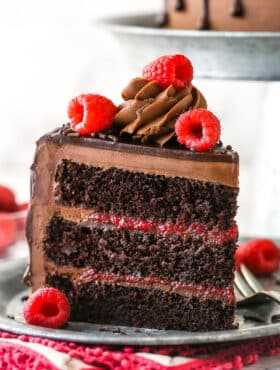 A slice of chocolate raspberry cake on a plate with a fork.