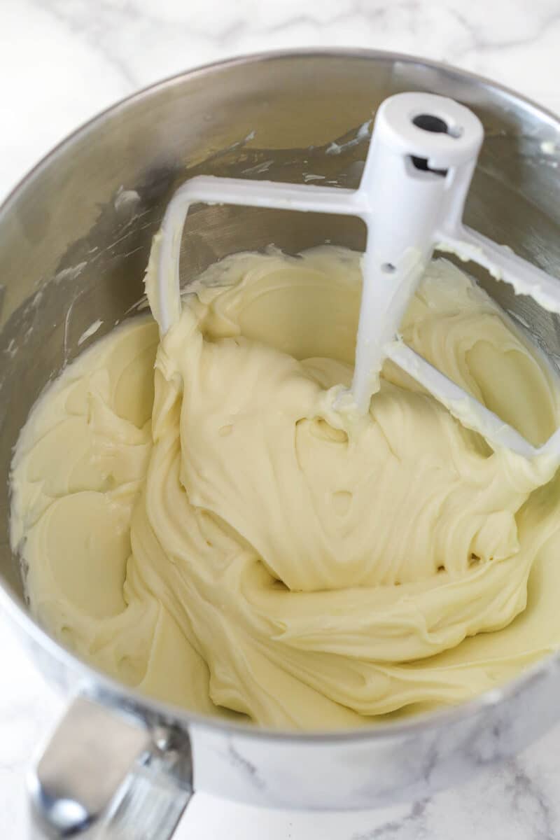 Mixing sour cream, lemon juice, and vanilla extract into cream cheese and sugar.