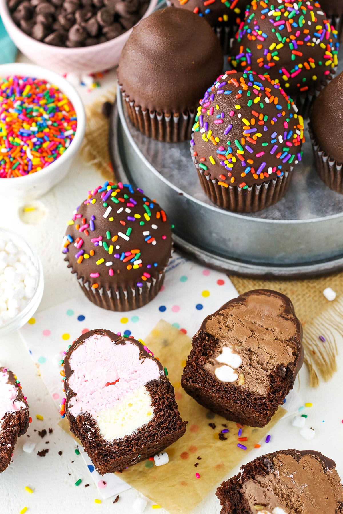 Overhead view of Ultimate Ice Cream Chocolate Cupcakes cut in half and more Ultimate Ice Cream Chocolate Cupcakes in a gray pan