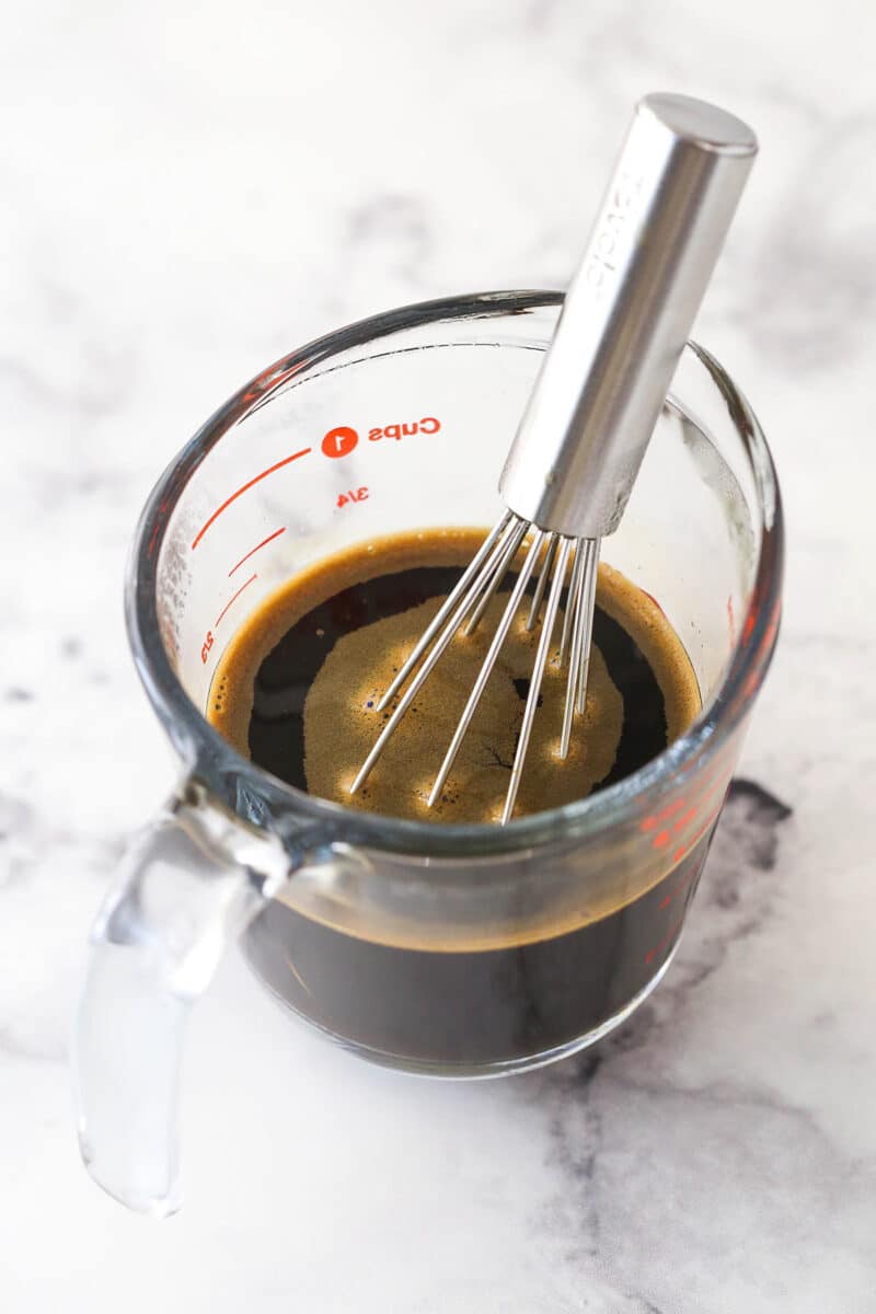 Whisking together hot water, sugar, and espresso in a measuring cup.