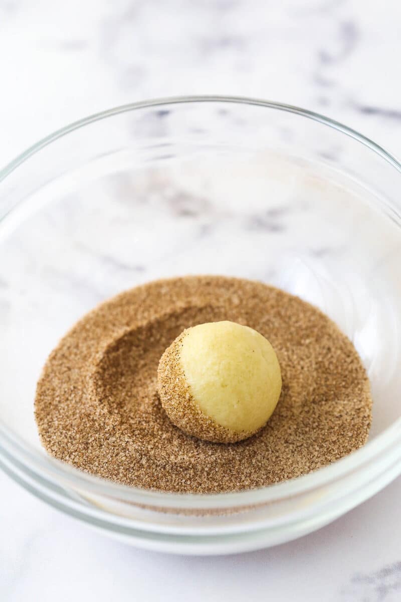 Rolling sugar cookie dough in cinnamon sugar.