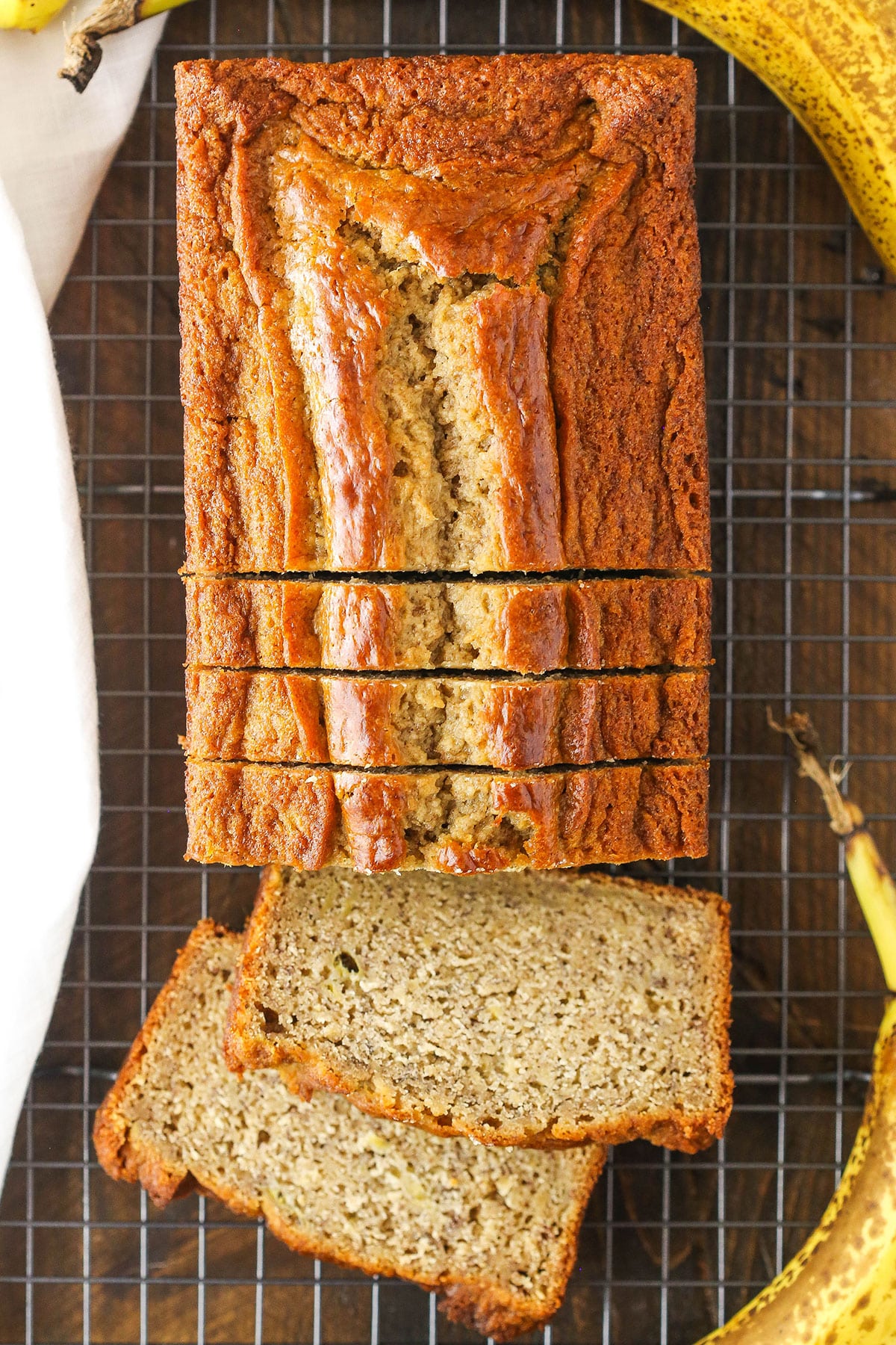 Overhead view of a loaf of Banana Bread with five slices cut off the end on a cooling rack