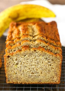 Side view of three Banana Bread slices leaning against the remaining banana bread loaf on a cooling rack