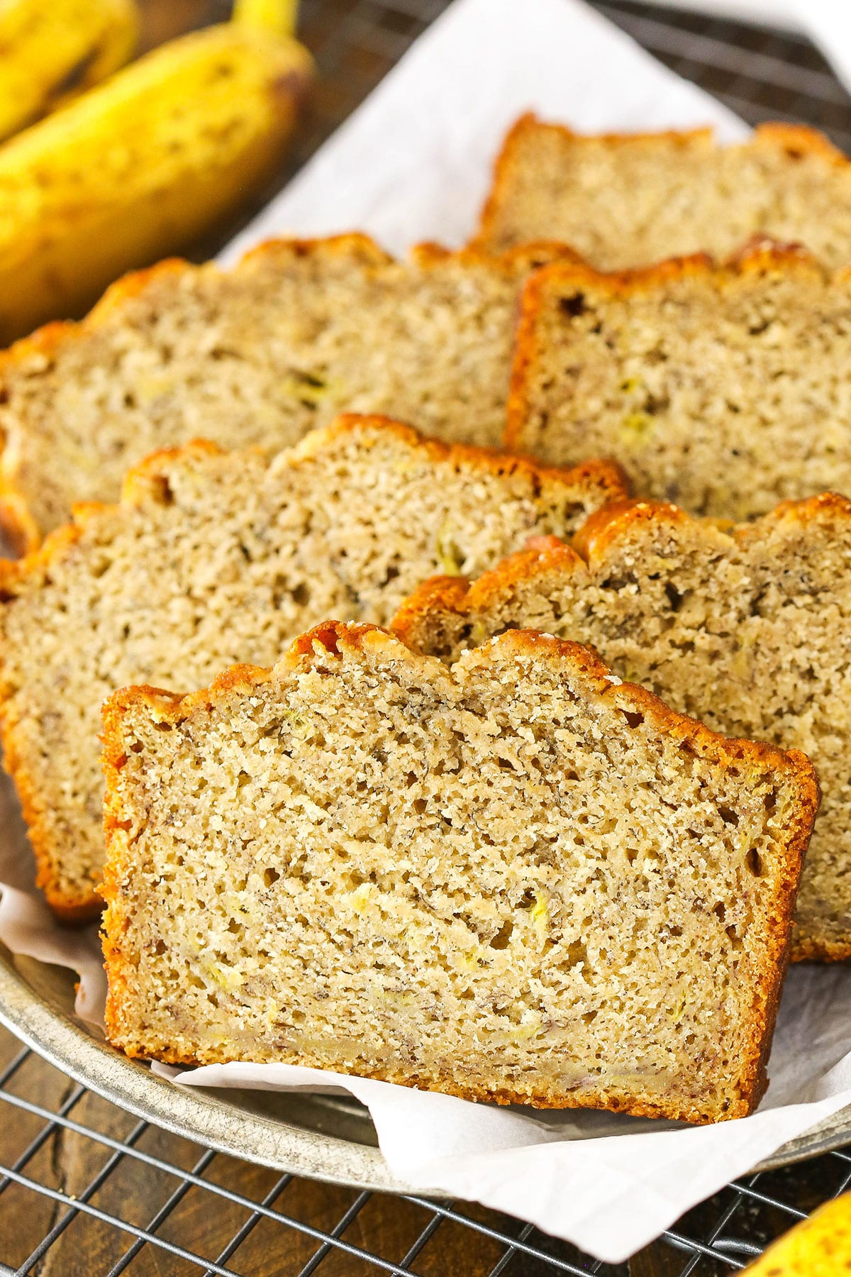 Six slices of Banana Bread stacked in a white dish lined with a white paper towel