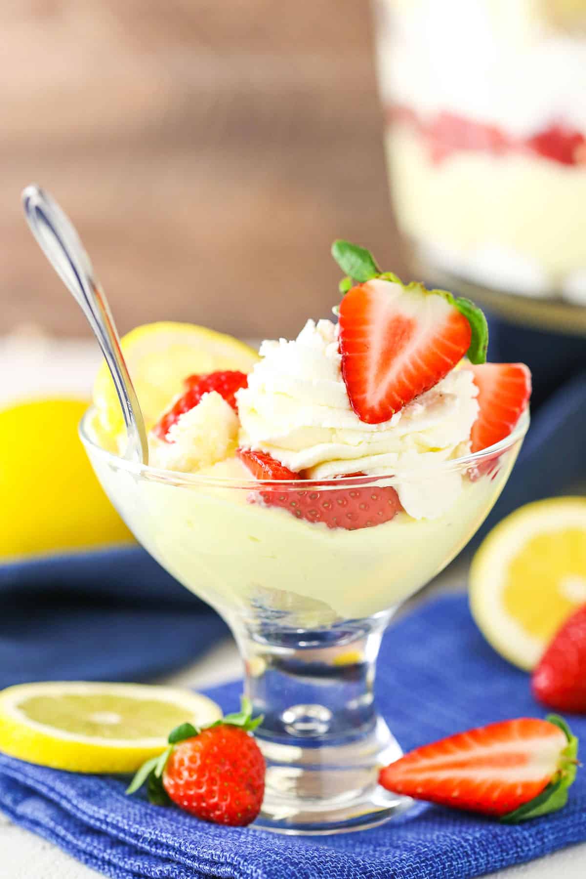 A serving of Lemon Strawberry Trifle in a clear glass dish with a silver spoon