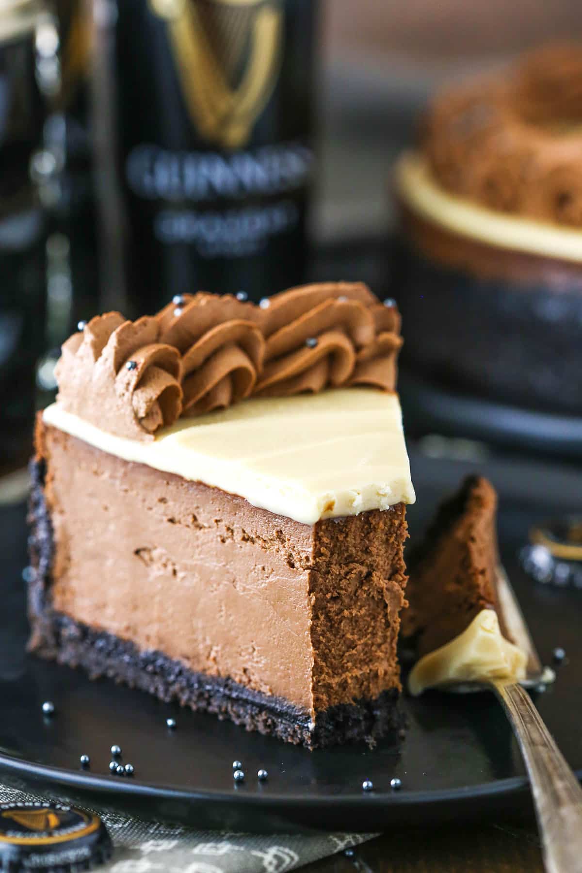 A slice of Guinness Chocolate Cheesecake with a bite taken out on a black plate