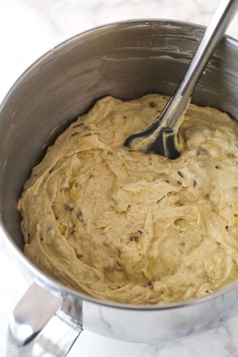 Folding crushed pineapple and toasted pecans into cake batter.