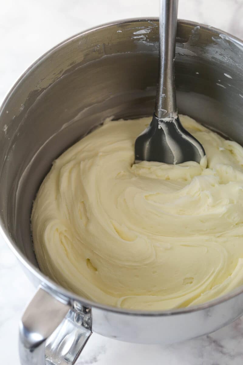 Cream cheese frosting in a mixing bowl with a rubber spatula.