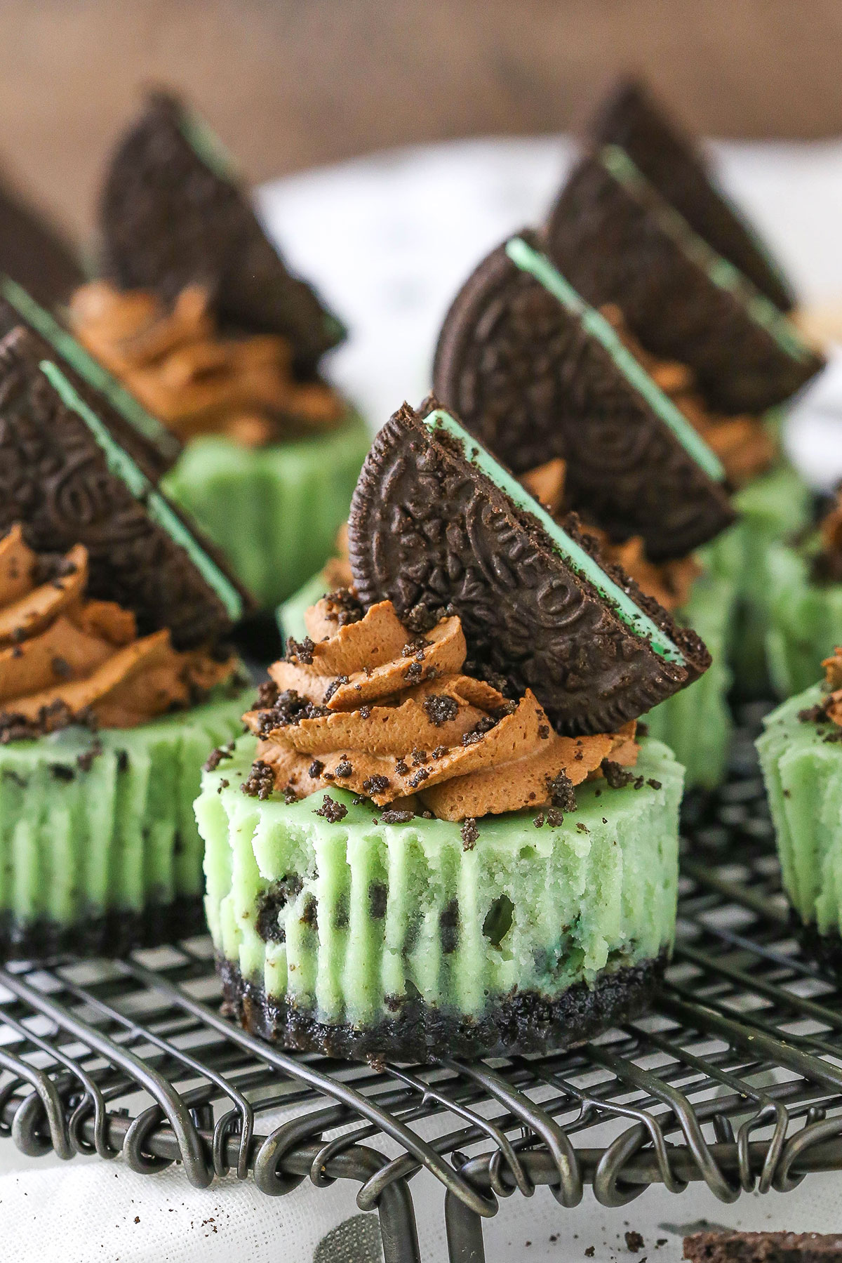 Side view of Mini Mint Chocolate Oreo Cheesecakes on a gray metal stand