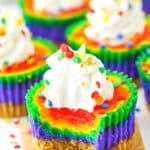 A Mini Rainbow Cheesecake with a bite removed on a white serving tray