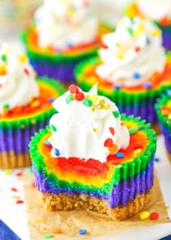 A Mini Rainbow Cheesecake with a bite removed on a white serving tray