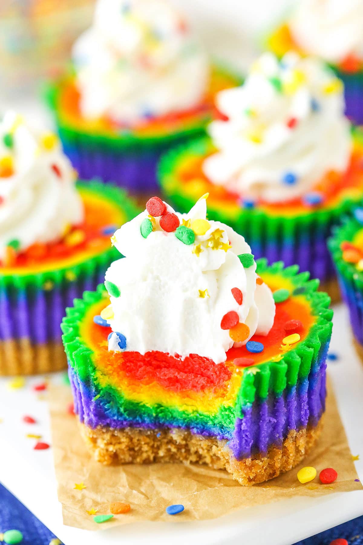 A Mini Rainbow Cheesecake with a bite removed on a white serving tray