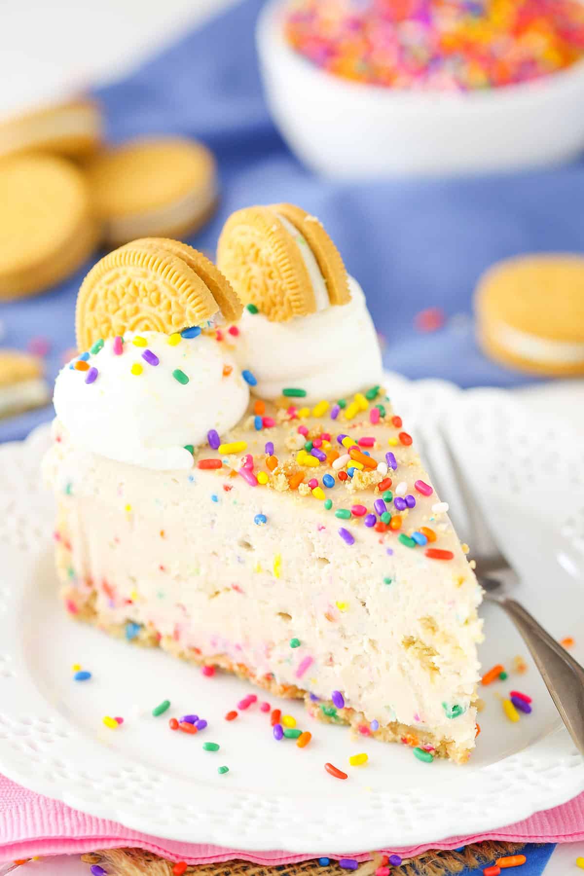 A slice of No-Bake Funfetti Oreo Birthday Cake Cheesecake next to a silver fork on a white plate