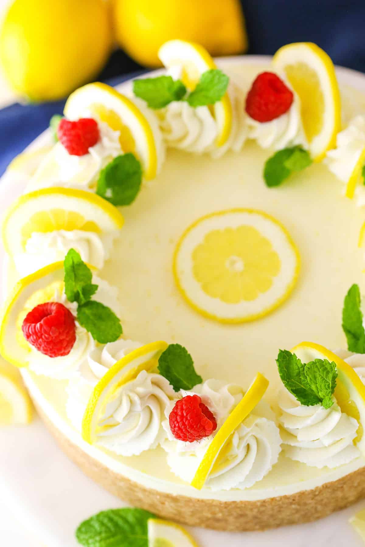 Overhead view of a whole No Bake Lemon Cheesecake on a white cake stand