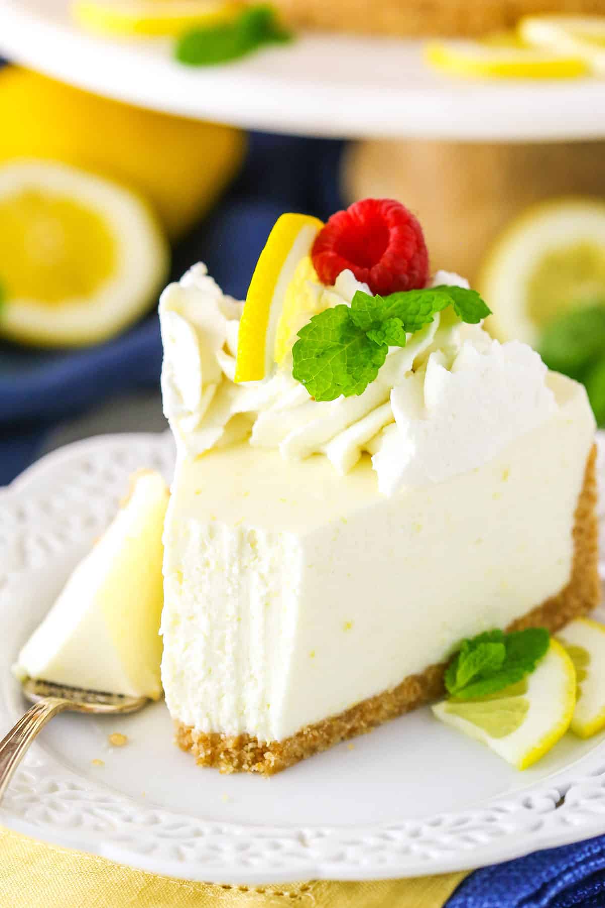 A slice of No Bake Lemon Cheesecake with a bite taken out next to a silver fork on a white plate