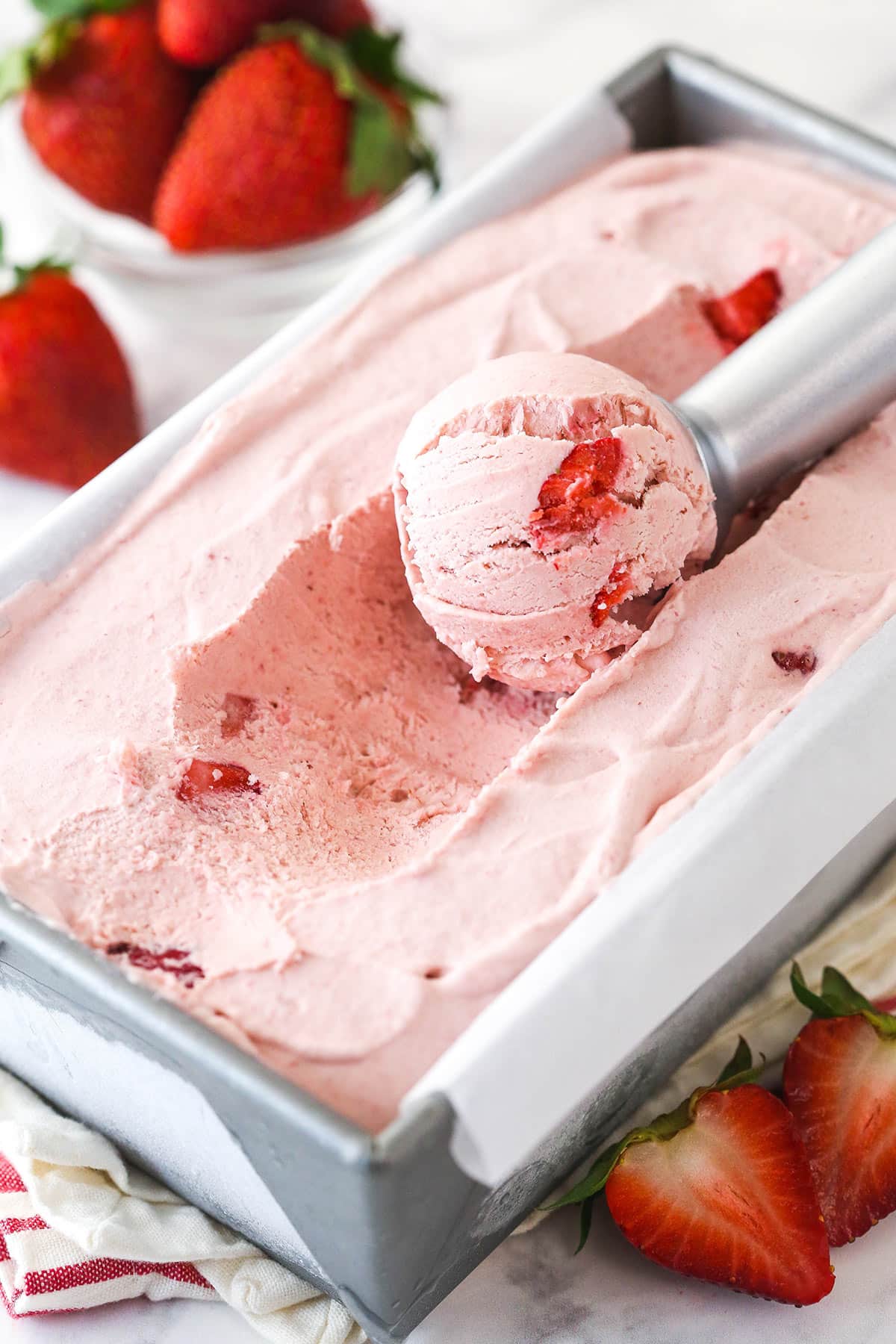 frozen no churn strawberry ice cream in loaf pan with a scoop taken out