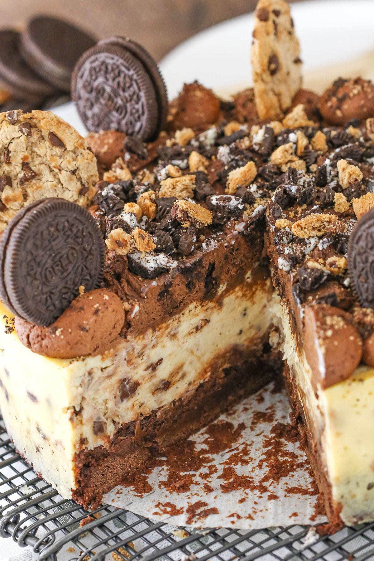 An Oreo Brookie Cheesecake with a slice removed on a metal cake stand
