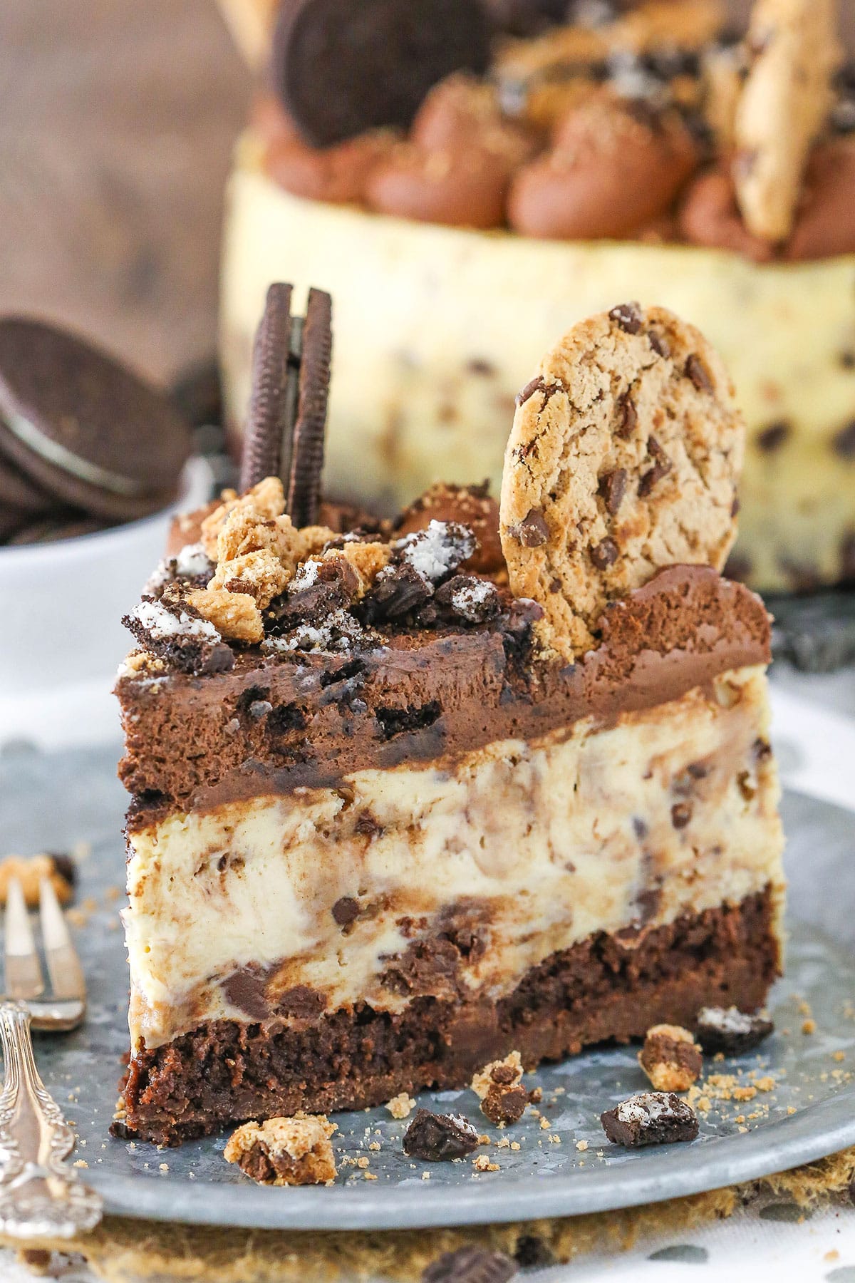 A slice of Oreo Brookie Cheesecake next to a silver fork on a gray plate