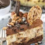 A slice of Oreo Brookie Cheesecake next to a silver fork on a gray plate