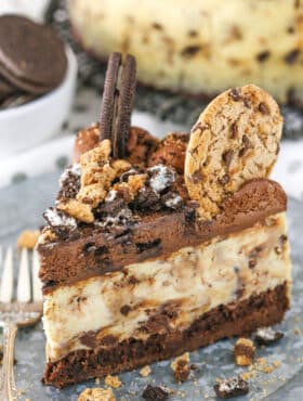 A slice of Oreo Brookie Cheesecake next to a silver fork on a gray plate