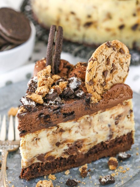 A slice of Oreo Brookie Cheesecake next to a silver fork on a gray plate