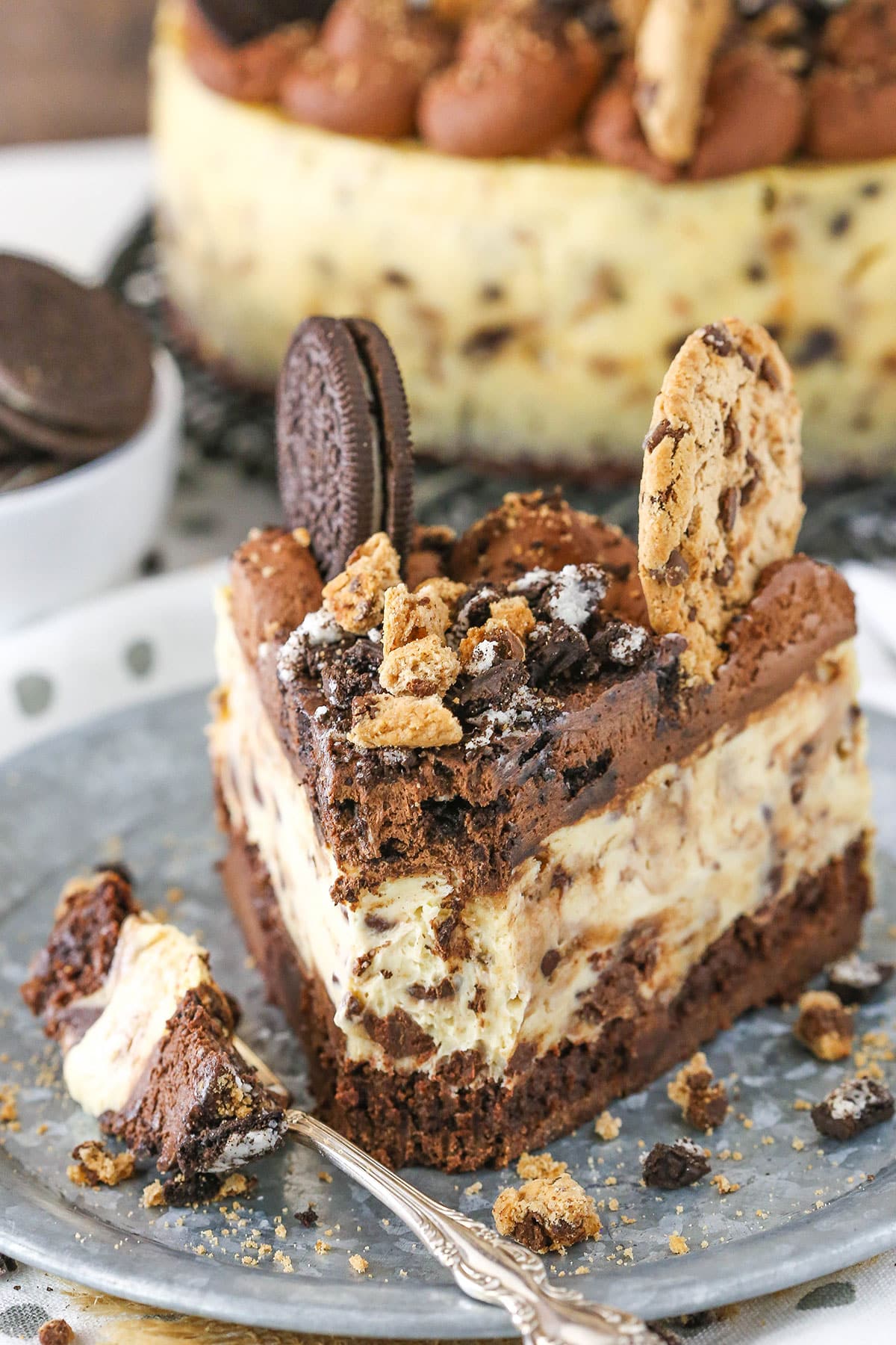 A slice of Oreo Brookie Cheesecake with a bite removed on a gray plate