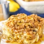 A square serving of Overnight Baked Banana French Toast Casserole next to a silver fork on a white plate