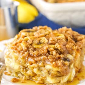 A square serving of Overnight Baked Banana French Toast Casserole next to a silver fork on a white plate